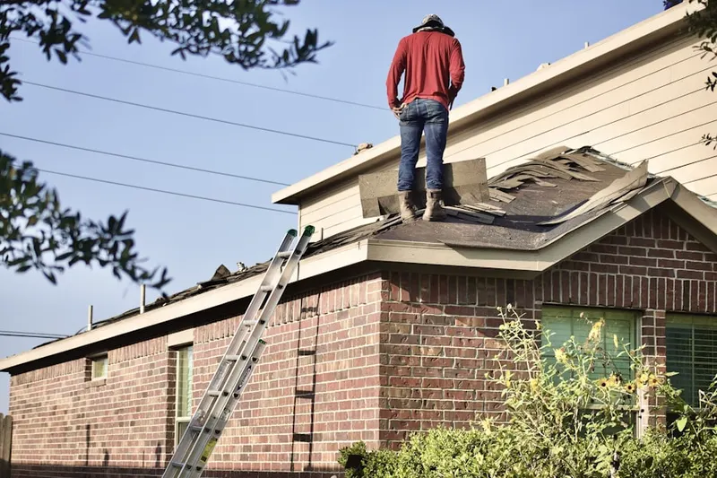 Professional roofer working on a residential roof in Manor